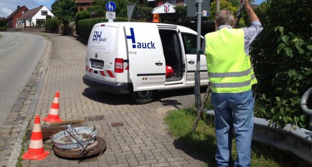 Firmenwagen IB-Hauck mit Arbeiter und offenem Kanaldeckel